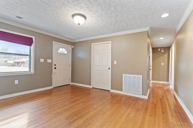 foyer featuring baseboards, visible vents, crown molding, and light wood finished floors