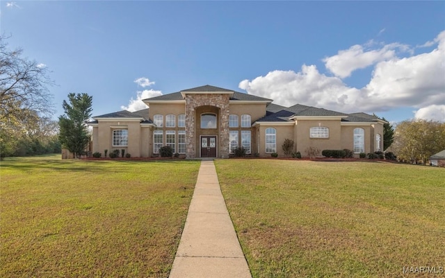 mediterranean / spanish-style house with a front yard, stone siding, and stucco siding