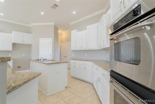 kitchen featuring light stone countertops, a center island, visible vents, and white cabinetry