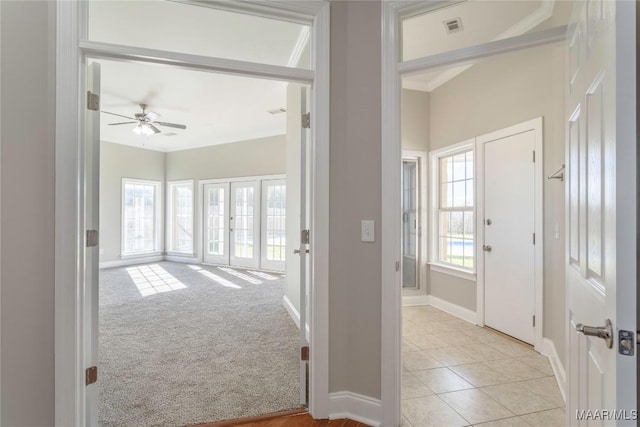 hall featuring light tile patterned floors, visible vents, baseboards, light colored carpet, and french doors