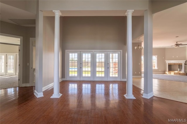 unfurnished living room with decorative columns and wood finished floors