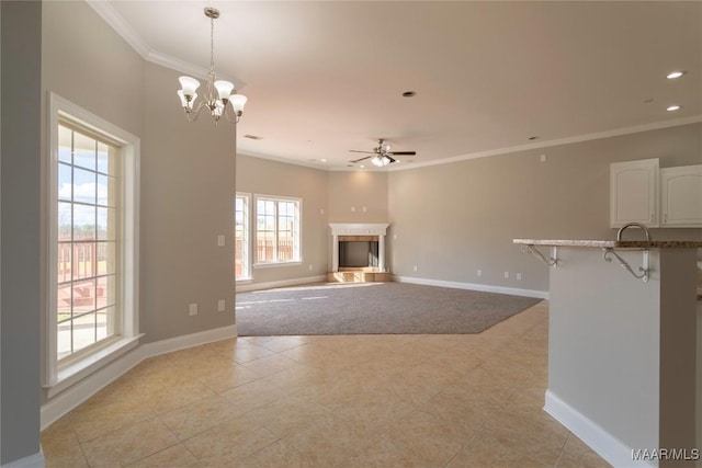 unfurnished living room featuring baseboards, ornamental molding, a fireplace with raised hearth, and recessed lighting