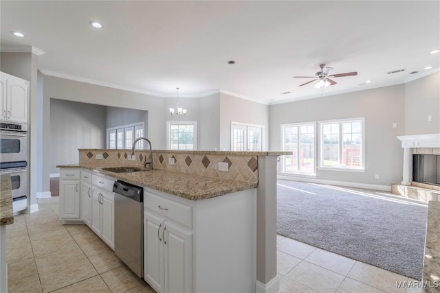 kitchen featuring decorative backsplash, a tiled fireplace, light colored carpet, stainless steel appliances, and a sink