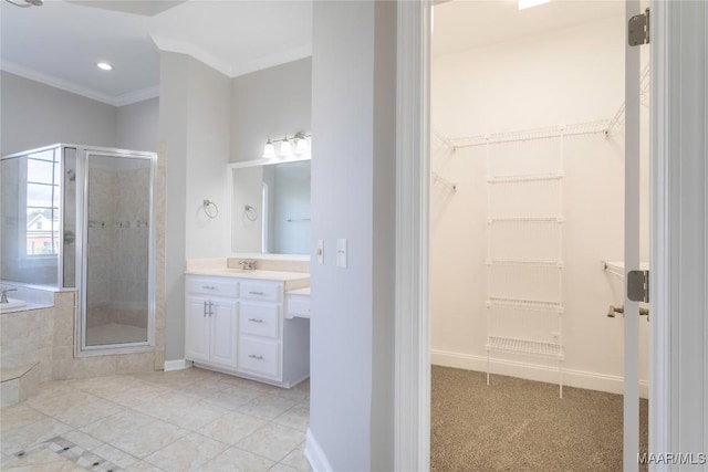 bathroom featuring ornamental molding, a stall shower, a walk in closet, and vanity