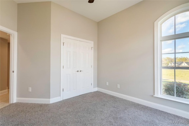 unfurnished bedroom featuring a ceiling fan, carpet, a closet, and baseboards