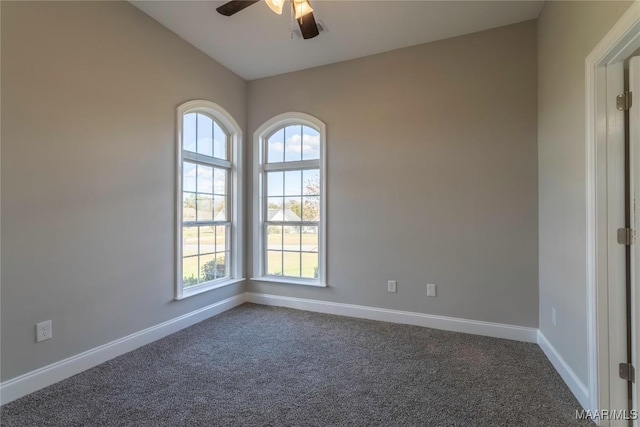 spare room featuring lofted ceiling, dark colored carpet, a ceiling fan, and baseboards