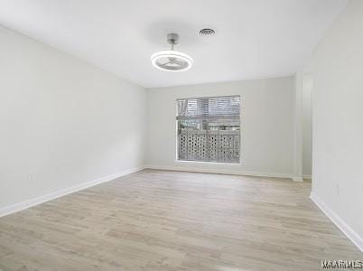 unfurnished room featuring baseboards, visible vents, and wood finished floors