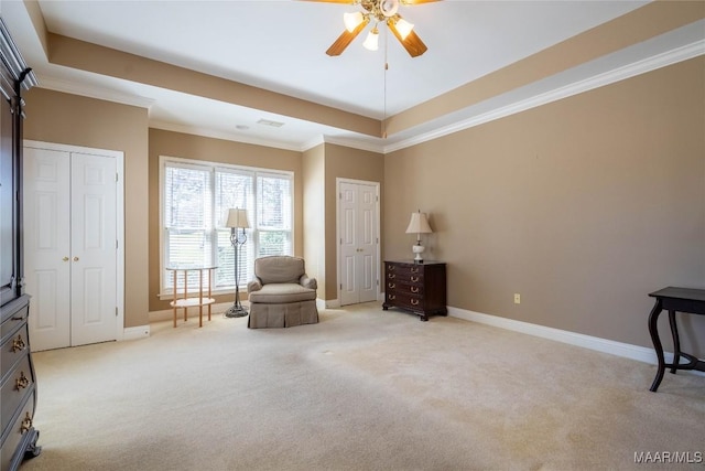 living area featuring a tray ceiling, light carpet, crown molding, and baseboards