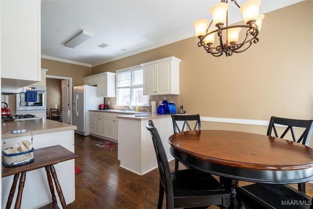 dining space featuring ornamental molding, a chandelier, visible vents, and dark wood-type flooring
