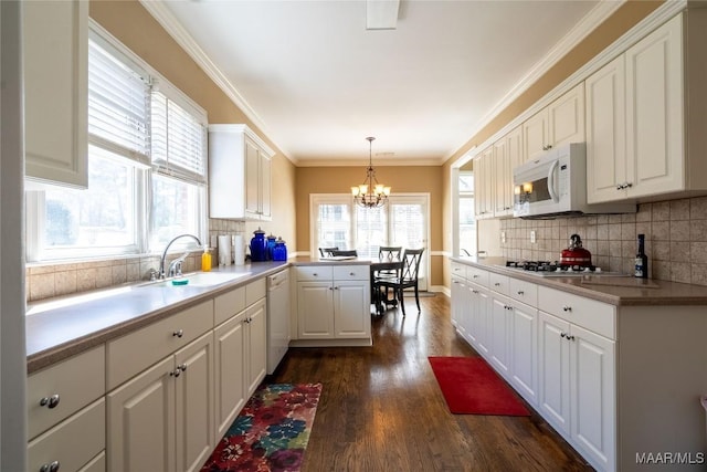 kitchen with white appliances, a sink, white cabinets, ornamental molding, and dark wood finished floors