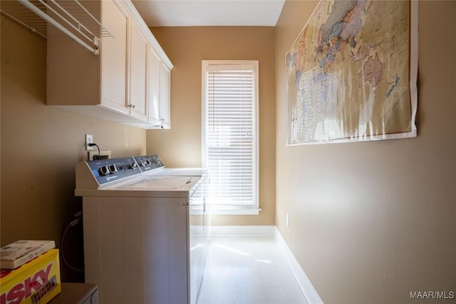 washroom featuring cabinet space, baseboards, and washer and dryer