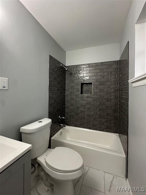 bathroom with toilet, marble finish floor, washtub / shower combination, and vanity