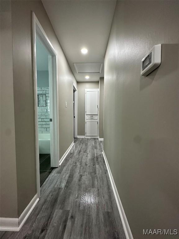 corridor with attic access, baseboards, and dark wood-style flooring