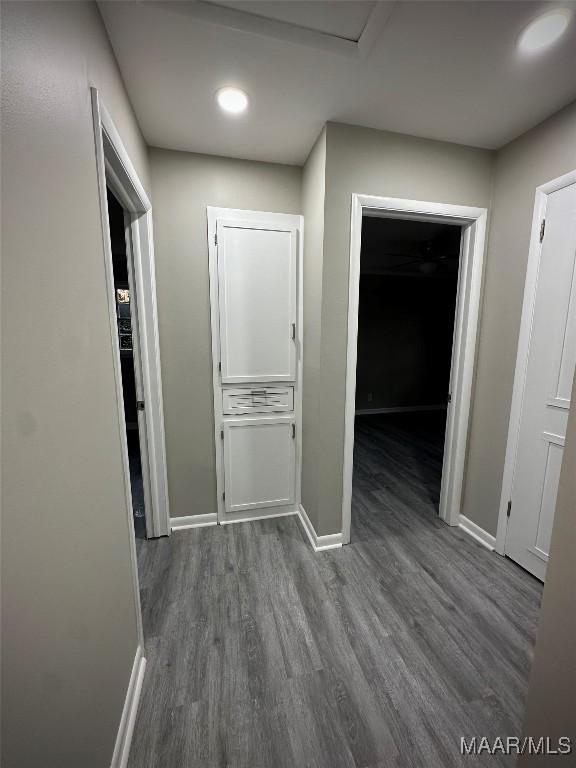 corridor featuring baseboards and wood finished floors