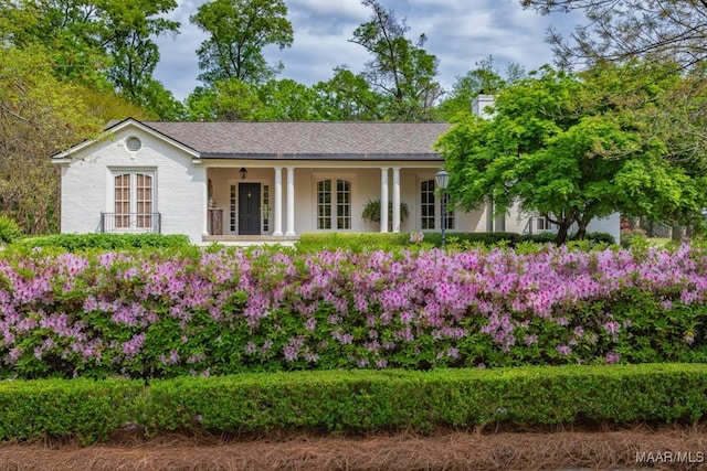 view of front of house with french doors, covered porch, and roof with shingles