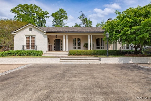 view of front of home featuring a porch, a chimney, and brick siding