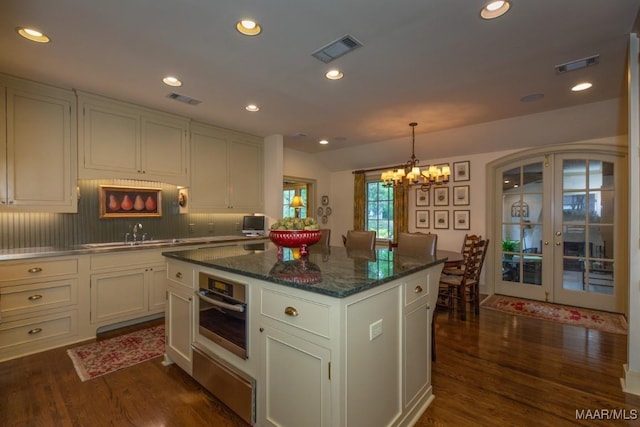 kitchen featuring visible vents, stainless steel oven, and white cabinets