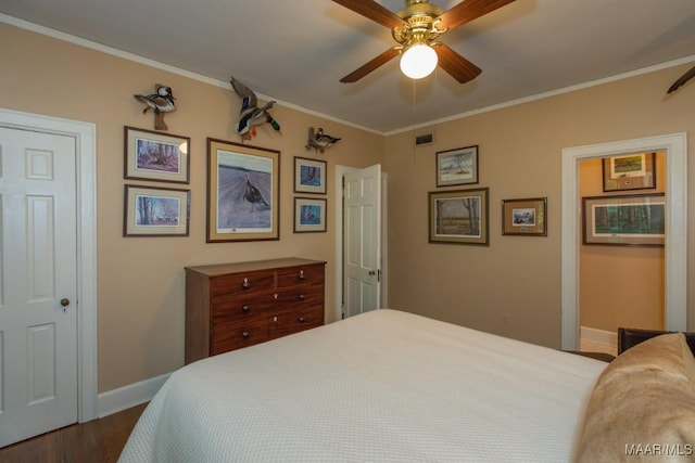 bedroom featuring ceiling fan, visible vents, baseboards, dark wood finished floors, and crown molding