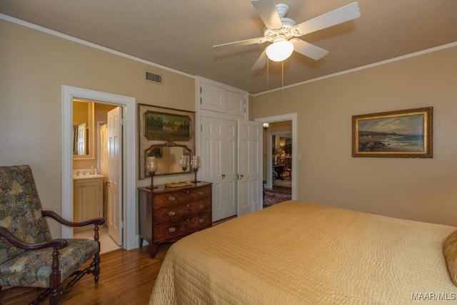 bedroom featuring visible vents, ensuite bath, ceiling fan, wood finished floors, and crown molding