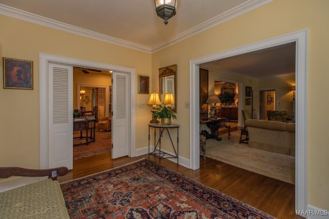 hallway with ornamental molding, dark wood-type flooring, and baseboards