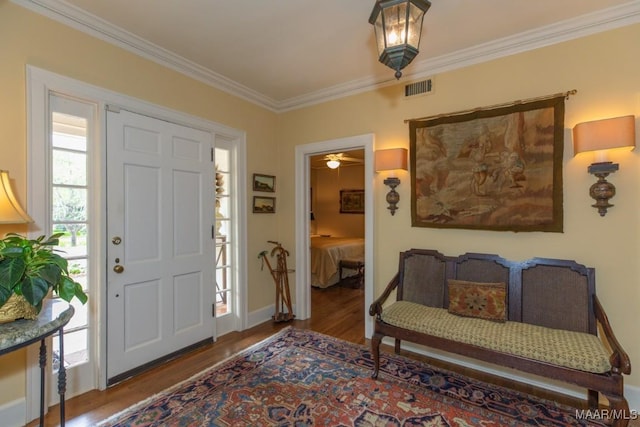 foyer featuring ornamental molding, visible vents, baseboards, and wood finished floors