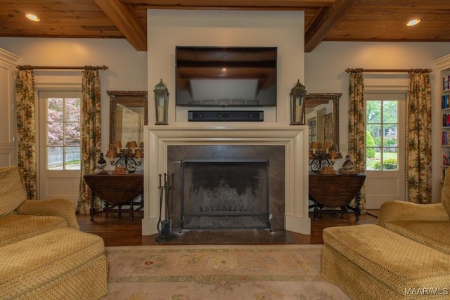 living area with wooden ceiling, a fireplace with flush hearth, beamed ceiling, and wood finished floors