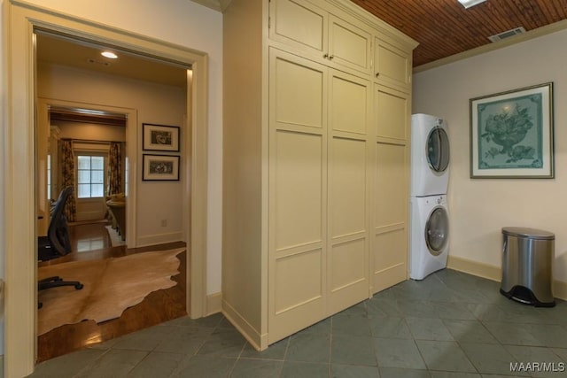 washroom featuring stacked washer and clothes dryer, visible vents, wood ceiling, dark tile patterned flooring, and baseboards