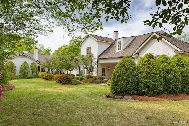 view of front of house with brick siding, a chimney, and a front lawn