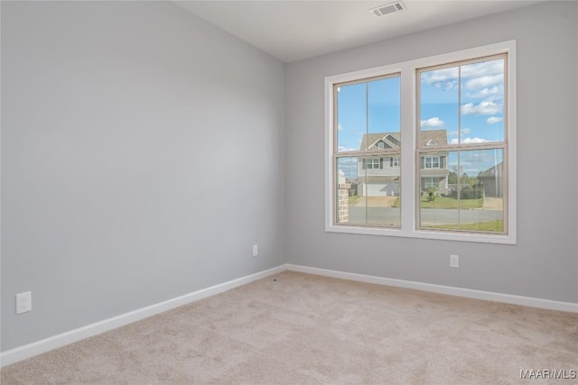 spare room with baseboards, visible vents, and light colored carpet