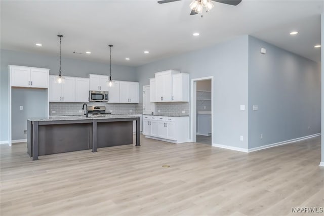 kitchen featuring a breakfast bar, tasteful backsplash, appliances with stainless steel finishes, a ceiling fan, and white cabinets