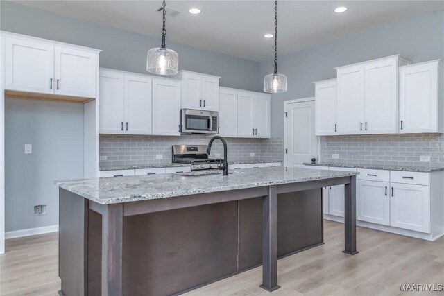 kitchen with appliances with stainless steel finishes, white cabinets, visible vents, and a sink