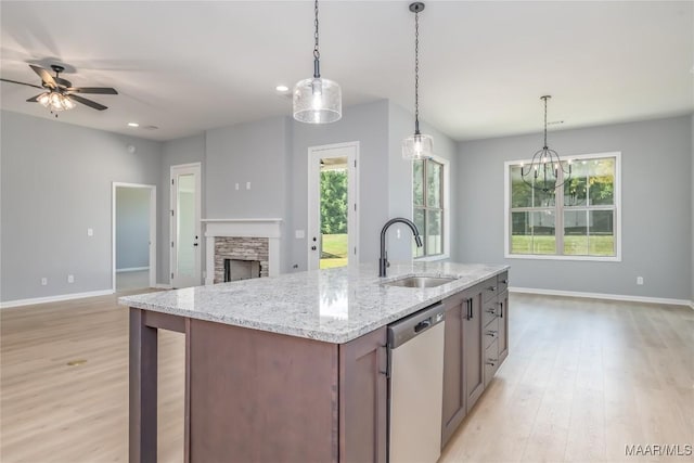 kitchen featuring light wood finished floors, stainless steel dishwasher, open floor plan, and a sink