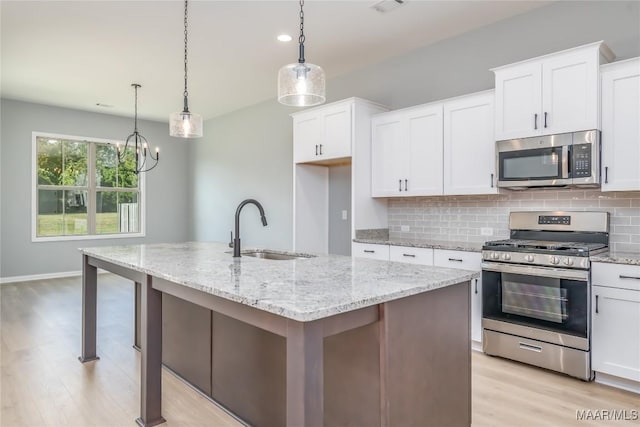 kitchen featuring stainless steel appliances, white cabinets, a sink, and decorative backsplash