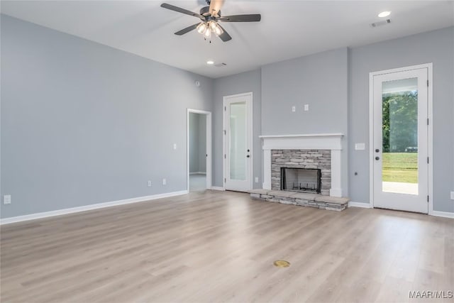 unfurnished living room with a ceiling fan, baseboards, a fireplace, and light wood finished floors