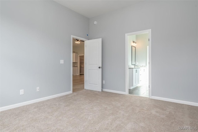 unfurnished bedroom with ensuite bath, carpet, and baseboards