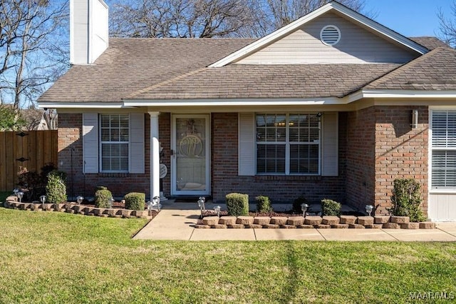 view of front of property with brick siding, a chimney, and a front yard