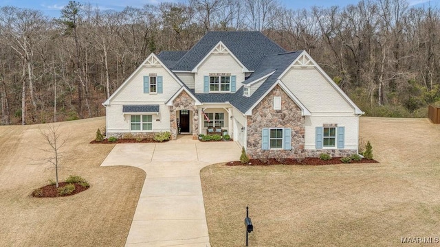 view of front facade with a front yard, stone siding, and driveway