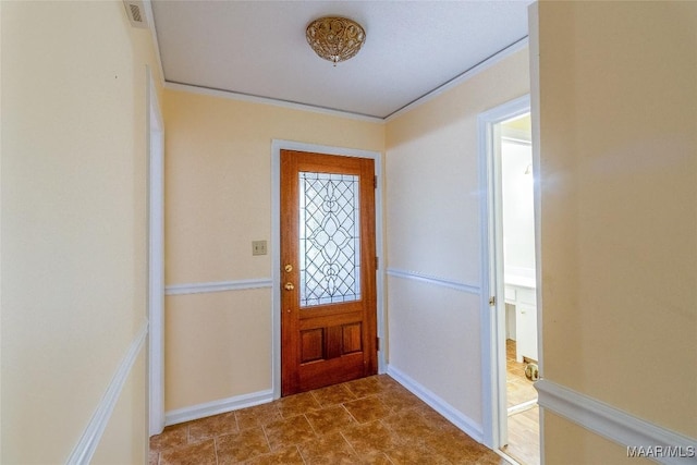 foyer featuring visible vents, crown molding, and baseboards