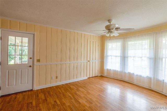 unfurnished room with crown molding, a textured ceiling, and wood finished floors