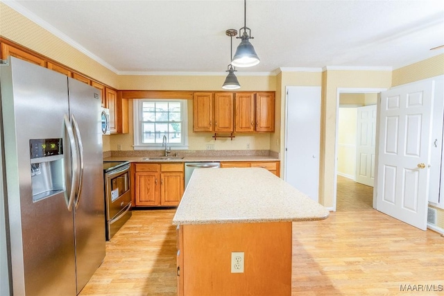 kitchen with a sink, stainless steel appliances, a kitchen island, and light wood-style flooring