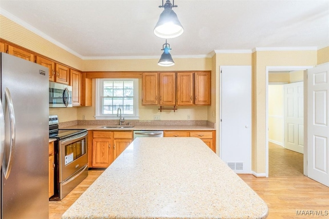 kitchen with visible vents, light wood-style flooring, stainless steel appliances, pendant lighting, and a sink