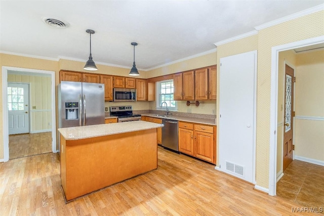 kitchen featuring a center island, light wood finished floors, stainless steel appliances, light countertops, and visible vents