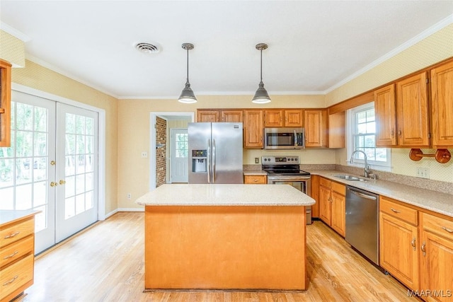 kitchen featuring visible vents, a center island, light countertops, stainless steel appliances, and a sink