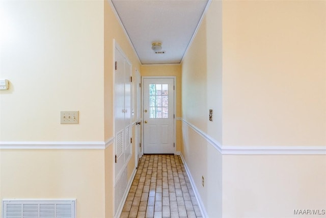 doorway featuring brick floor, visible vents, and baseboards