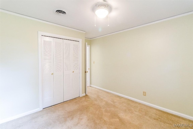 unfurnished bedroom featuring light carpet, visible vents, baseboards, a closet, and crown molding