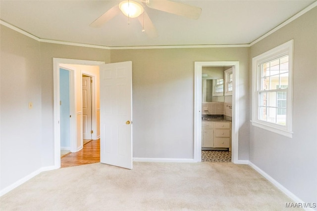 unfurnished bedroom featuring light carpet, baseboards, ensuite bathroom, and crown molding