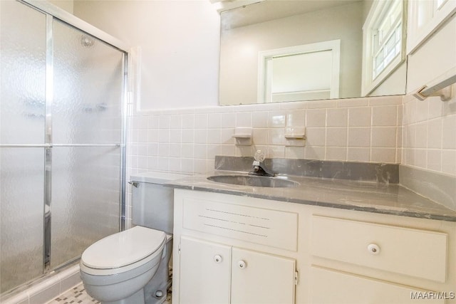 full bath with tile walls, a shower stall, vanity, and toilet