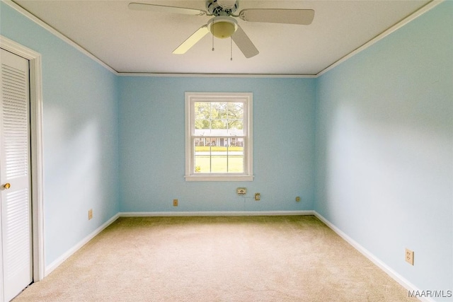 spare room with ceiling fan, carpet floors, baseboards, and crown molding