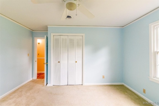 unfurnished bedroom with carpet floors, visible vents, baseboards, ornamental molding, and a closet