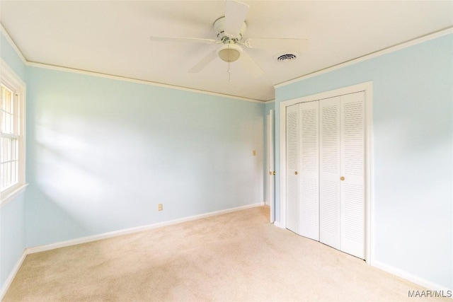 unfurnished bedroom featuring carpet floors, a closet, visible vents, ornamental molding, and baseboards